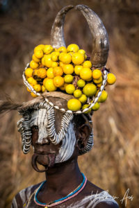 Mursi woman in a headdress of metal, fruit and horns , Omo Valley Ethiopia