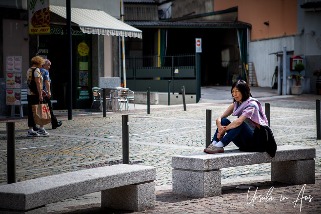 Woman seated on a stone bench, Piazzale Stazione, Tirano Italy