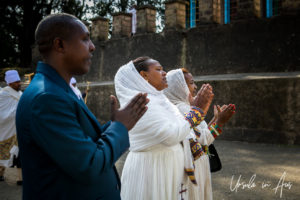Man in a suit, woman in a white headscarf praying, Entoto Maryam Church, Ethiopia