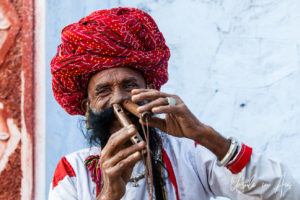 Rajasthani man in a red turban playing Nose Flutes Pushkar India