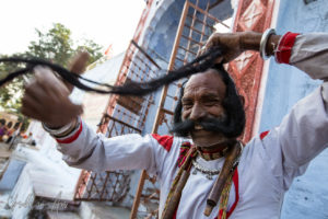 Rajasthani musician tying up his long moustache, Pushkar India