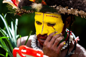 Huli wigman applying facepaint, Paiya Village Papua New Guinea