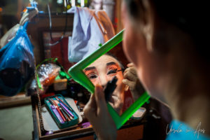 Chinese opera performer applying eyeliner in a mirror, Chao Zhou Shi Kong Shrine, Bangkok