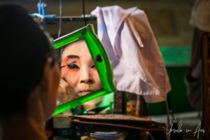 Chinese opera performer applying eyeliner in a mirror, Chao Zhou Shi Kong Shrine, Bangkok