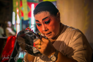 Chinese opera performer applying makeup in a mirror, Chao Zhou Shi Kong Shrine, Bangkok