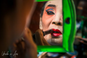 Chinese opera performer applying lipstick in a mirror, Chao Zhou Shi Kong Shrine, Bangkok