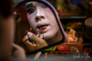 Chinese opera performer applying lipstick in a mirror, Chao Zhou Shi Kong Shrine, Bangkok