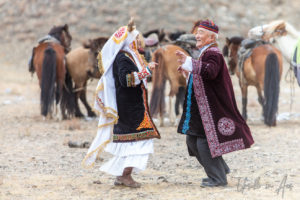 Old man and woman dancing in traditional Kazakh dress, Golden Eagle Festival, Olgii Mongolia