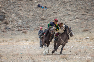 Two horseback Kazakh eagle hunters fighting over a sheep, Golden Eagle Festival, Olgii Mongolia