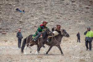 Two horseback Kazakh eagle hunters fighting over a sheep, Golden Eagle Festival, Olgii Mongolia