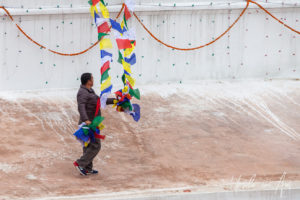 Man guiding strings of prayer flags down Boudhanath stupa, Kathmandu Nepal
