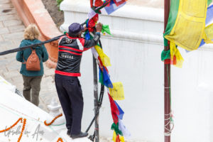 Tying prayer flags at the outer edge of Boudhanath stupa, Kathmandu Nepal