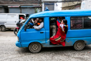 Woman hanging out of an overloaded taxi-van, Kathmandu Nepal