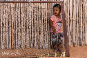 Bedouin child in behind wire mesh, Wahiba Sands, Oman