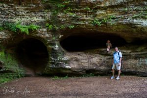 Man and child in front of holes in Black Hand Sandstone, Hocking Hills State Park, Ohio
