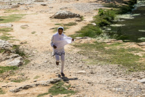 Girl in a white hijab running, Wadi Bani Khalid, Oman