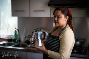A Nepali woman in a kitchen with a moka pot.