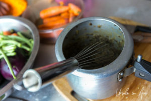 Hand whisk in a pot of daal.