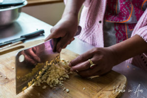 Woman's hands chopping garlic.