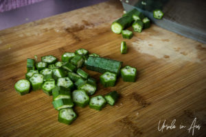 Detail: okra slices on a wooden cutting board.