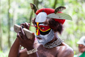 Western Highland man applying face paint in a hand mirror, Paiya Village, Papua New Guinea.