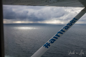 View of rain on the Pacific Ocean and an Air Fraser strut from inside the plane, Queensland Australia