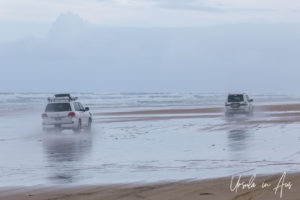 Two 4WD vehicles driving in low water on Seventy-Five Mile Beach, Fraser Island, Queensland Australia