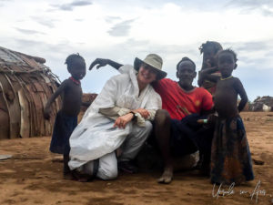 White woman in a raincoat with a Daasanach man and children, Omo Valley Ethiopia