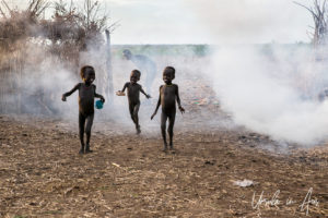 Three children in fire smoke, Daasanach Village, Omo Valley Ethiopia