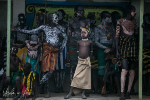 Villagers in clay paint crowded onto a building porch, Dus Ethiopia