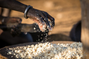 Woman's hand in a pan of sorghum, Omo Valley Ethiopia
