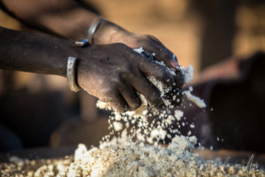 Woman's hands in a pan of sorghum, Omo Valley Ethiopia