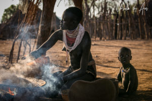 Woman stirring a pan of sorghum over a fire, Omo Valley Ethiopia