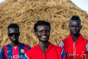 Three Ethiopian men in Red, Round-bottom clay pots on the ground, Dus Village, Omo Valley Ethiopia