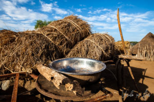 A metal bowl in front of two bales of grain, Dus Village, Omo Valley Ethiopia
