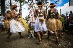 Grass skirt costumes and red and white triangle prop: dancers, Mt Hagen PNG