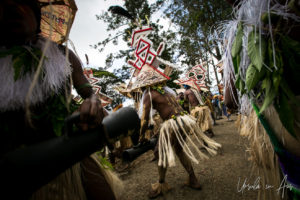 Grass skirt costumes and red and white triangle hats: dancers, Mt Hagen PNG