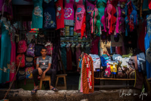 Egyptian man seated outside a women's clothing store, Luxor