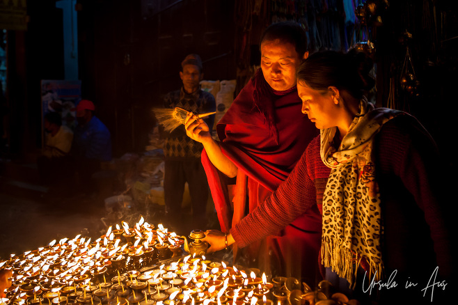 Tibetan monk and a woman light lamps, Boudhanath, Kathmandu Nepal
