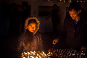 Nepali man and girl lighting lamps, Boudhanath, Kathmandu