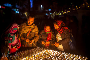Nepali man and women lighting lamps, Boudhanath, Kathmandu