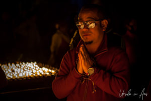 Portrait: A monk praying in the light of lamps, Boudhanath, Kathmandu