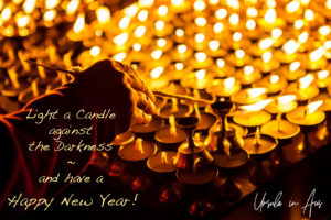 Hand lighting oil lamps, Boudhanath, Kathmandu Nepal. Text: Happy New Year!