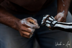 Close-up: skeleton-man painting a boy's hands, Mt Hagen Papua New Guinea.