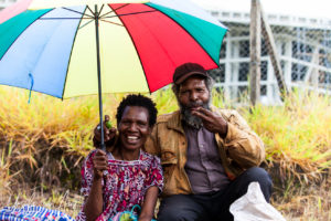 Papuan couple under a rainbow umbrella, Mt Hagen Papua New Guinea.