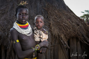 Girl with a toddler in front of a Dus Village house, Omo River Ethiopia