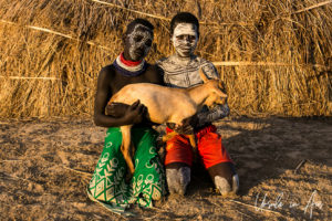 Two young Kara people in face paint with a kid, Dus Village Ethiopia