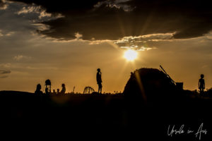 A Dus Village hut and people silhouetted by afternoon sun, Omo Valley Ethiopia