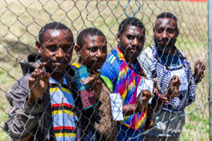 Papuan men outside a mesh fence, Mt Hagen Cultural Show, PNG