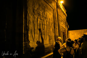 Guide at the relief of Thoth Isis King Ptolemy XIII Sekhmet and Horus, Kom Ombo Temple after dark, Egypt